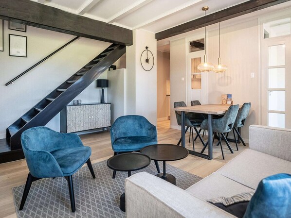 Una sala de estar moderna con una escalera, un comedor con una mesa y sillas, y un sofá.