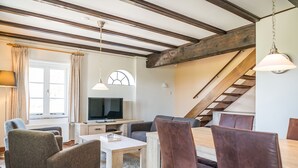 A modern living room with a television, seating, and a staircase. - Seals Cozy Farm Stay (De Cocksdorp Texel)