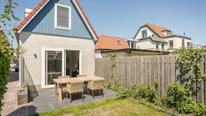 A house with a blue exterior, a brick patio, and a wooden fence.