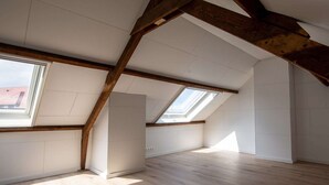 An attic room with exposed wooden beams, skylights, and a sloped ceiling. - Nice holiday home in Ostend by the sea with a terrace (Oostende)