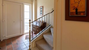 A staircase with a wooden handrail leading to a landing with a small table and chairs. - Nice holiday home in Ostend by the sea with a terrace (Oostende)