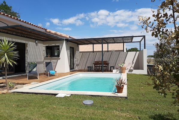 Relax by the rectangular pool surrounded by a deck, or enjoy meals on the adjacent shaded patio with a wooden table and chairs.