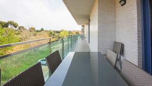 A balcony with a glass railing, a table, and two chairs. - Belvilla by OYO Apartamento Augusta (Cambrils)