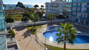 A modern building with a pool area, including a circular pool and palm trees. - Belvilla by OYO Apartamento Augusta (Cambrils)