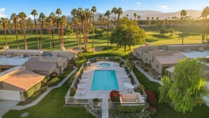 Un resort con piscina, varias edificaciones y un campo de golf al fondo.