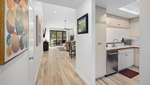 Una cocina moderna con armarios blancos, lavavajillas de acero inoxidable y encimera de madera.