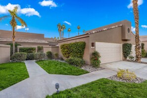 A residential area with a well-maintained lawn, a garage, and palm trees. - Modern & Relaxing Condo | Stunning Fairway and Mountain Views | Ideal Vacation Retreat (Palm Desert)