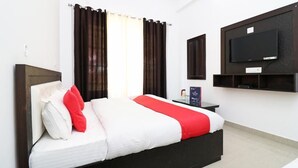 Een moderne hotelkamer met een groot bed, een flatscreen televisie aan de wand en een kleine tafel met een lamp.