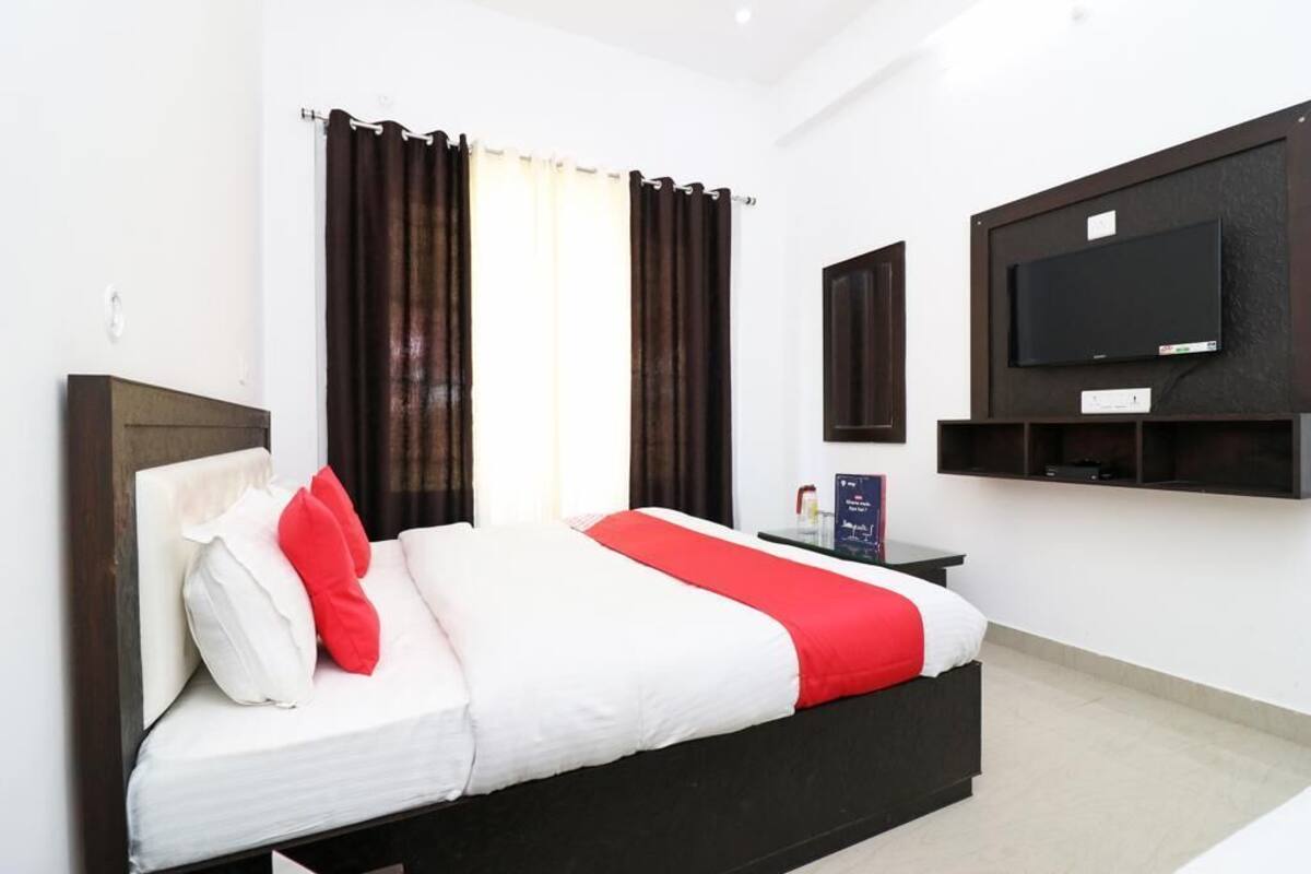 Habitación de hotel moderna con una cama grande, un televisor de pantalla plana en la pared y una mesita de noche con lámpara.