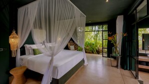 Een slaapkamer met een hemelbed, een hanglamp en uitzicht op groen.