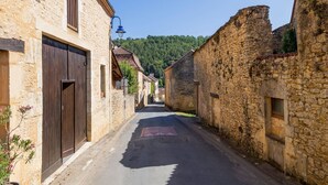 Une rue étroite bordée de bâtiments en pierre, caractérisée par une architecture traditionnelle et un ciel dégagé.