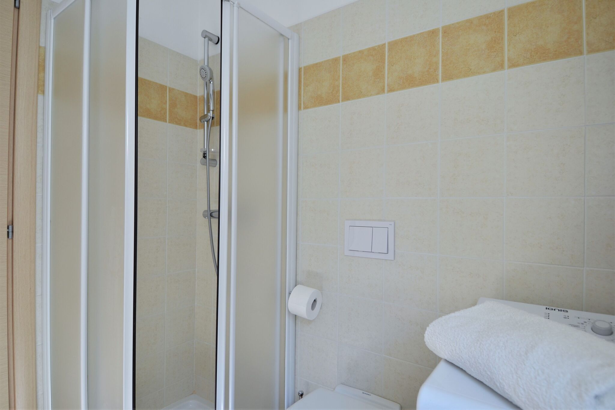 A bathroom with a glass shower enclosure, a toilet, and a towel rack.