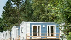 Une rangée de maisons mobiles dotées d’une terrasse en bois et d’une seule porte visible.