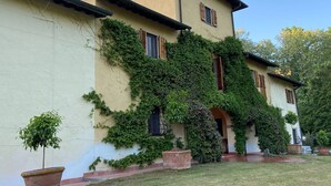 A two-story building with a yellow facade, wooden shutters, and ivy-covered walls.