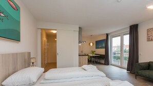 Hotellihuone, jossa on kaksi sänkyä, työpöytä, tuoli ja parveke, jossa on verhot.