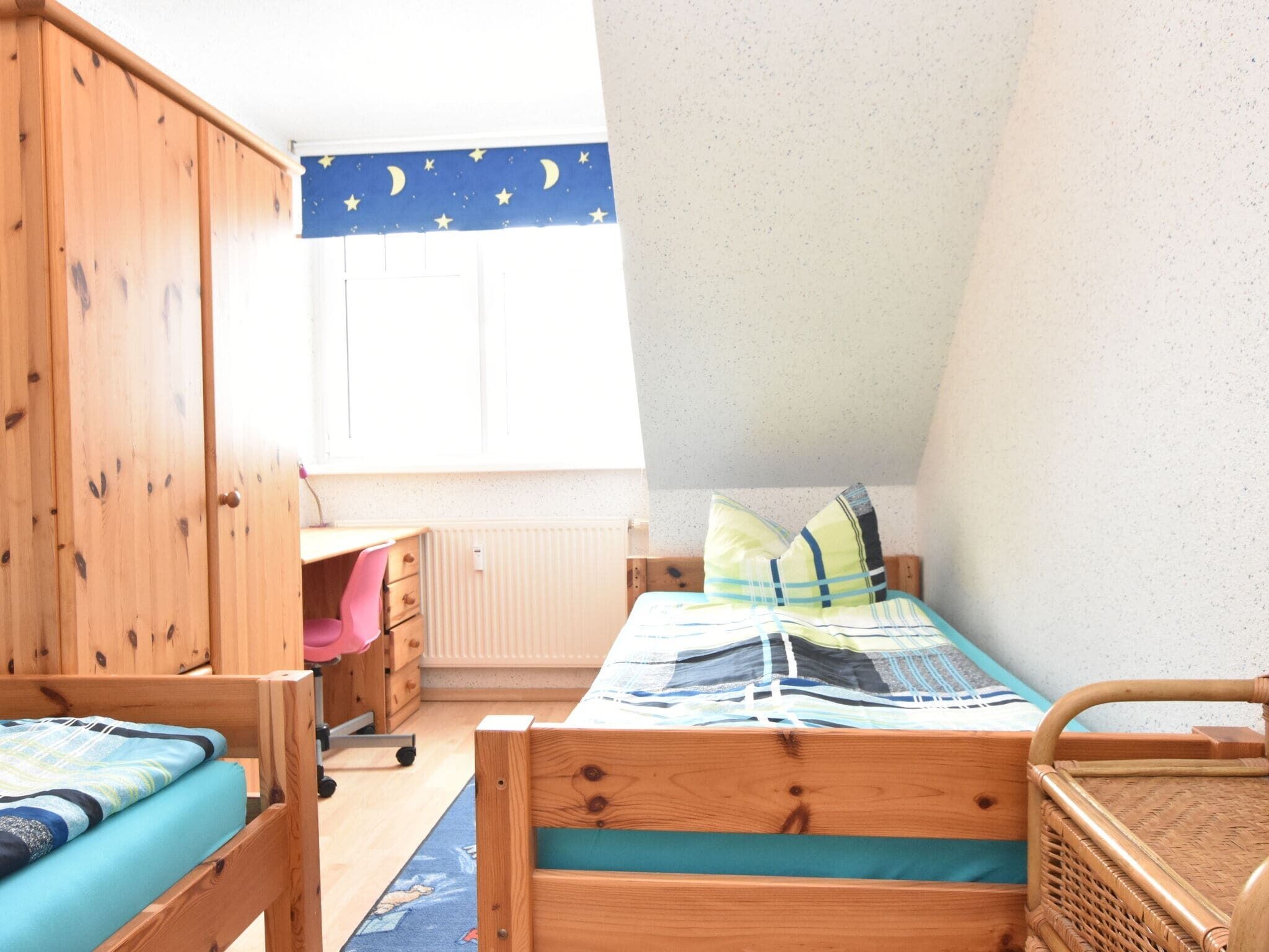 A bedroom with a bunk bed, a desk, and a wardrobe.