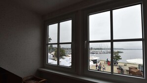 Una habitación con un amplio ventanal que da a un puerto deportivo con barcos y gente.