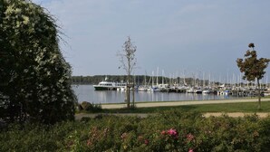 Un puerto deportivo con barcos amarrados, rodeado de follaje y un cielo despejado.