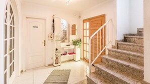 Passadís net i ben il·luminat amb una escala que condueix a una porta de fusta amb la inscripció "PRIVADO".