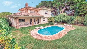 Una casa de dos pisos amb una piscina, envoltada d'un jardí ben cuidat i diferents plantes.