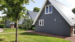 A modern house with a grey exterior and white trim, number 45, surrounded by a well-maintained lawn and trees.