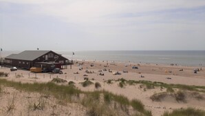 A beachside building with a flat roof and a large open area in front.