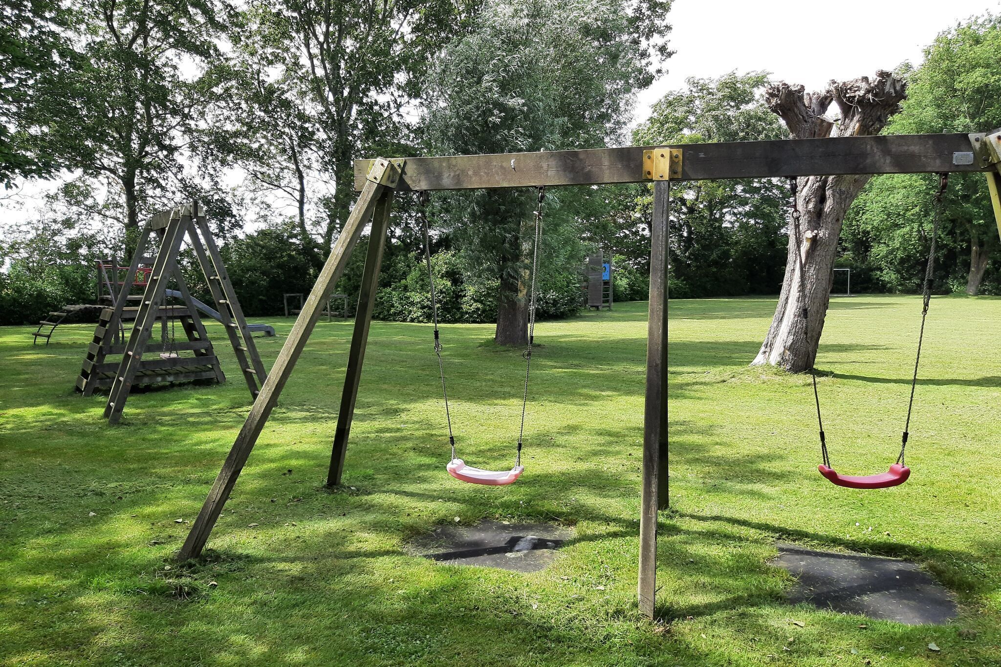 A playground with swings and a slide in a park.