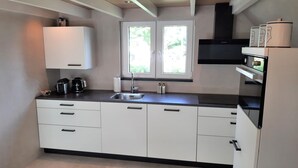 A modern kitchen with white cabinets, a black countertop, a built-in oven, and a window with a view of greenery outside.