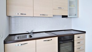Una cocina moderna con armarios de madera clara, un lavamanos de acero inoxidable y un horno empotrado.