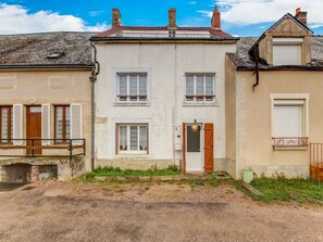Uma fileira de casas de dois andares com porta central e janelas, uma pequena área de jardim e um acesso pavimentado.