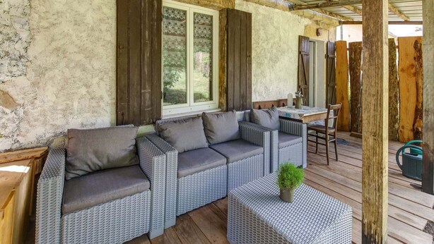 Un espacio de estar al aire libre con techo, mobiliario de mimbre y terraza de madera.