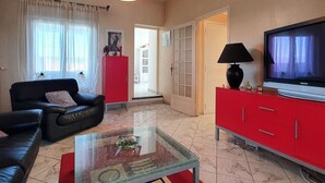 A living room with a sofa, a red cabinet, a television, and a glass coffee table. - Majestic Villa in Homps with Private Pool (Homps)