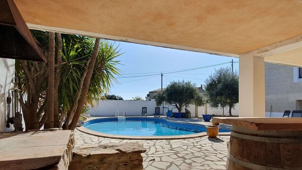 A swimming pool with stone tiles, a wooden barrel, and a covered seating area. - Majestic Villa in Homps with Private Pool (Homps)