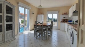 A spacious kitchen with a dining area, a washing machine, and a view of the outside. - Majestic Villa in Homps with Private Pool (Homps)