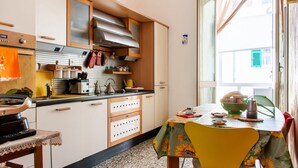 Een keuken met houten kastjes, een fornuis en een eethoek met een tafel en stoelen.