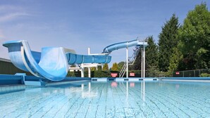 Une piscine avec un toboggan bleu et un poste de surveillance pour les sauveteurs.