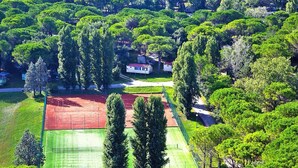 Ett flygbildsbild av ett bostadsområde med hus, grönområden och en tennisbana.