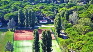 An aerial view of a residential area with houses surrounded by lush greenery and sports fields. - Belvedere AC Flat in Grado Resort (Belvedere di Aquileia)