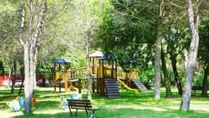A playground with slides and climbing structures, surrounded by trees and a bench. - Belvedere AC Flat in Grado Resort (Belvedere di Aquileia)