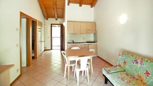 Una cocina con armarios de madera, una mesa de comedor con sillas y un sofá estampado con motivos florales.