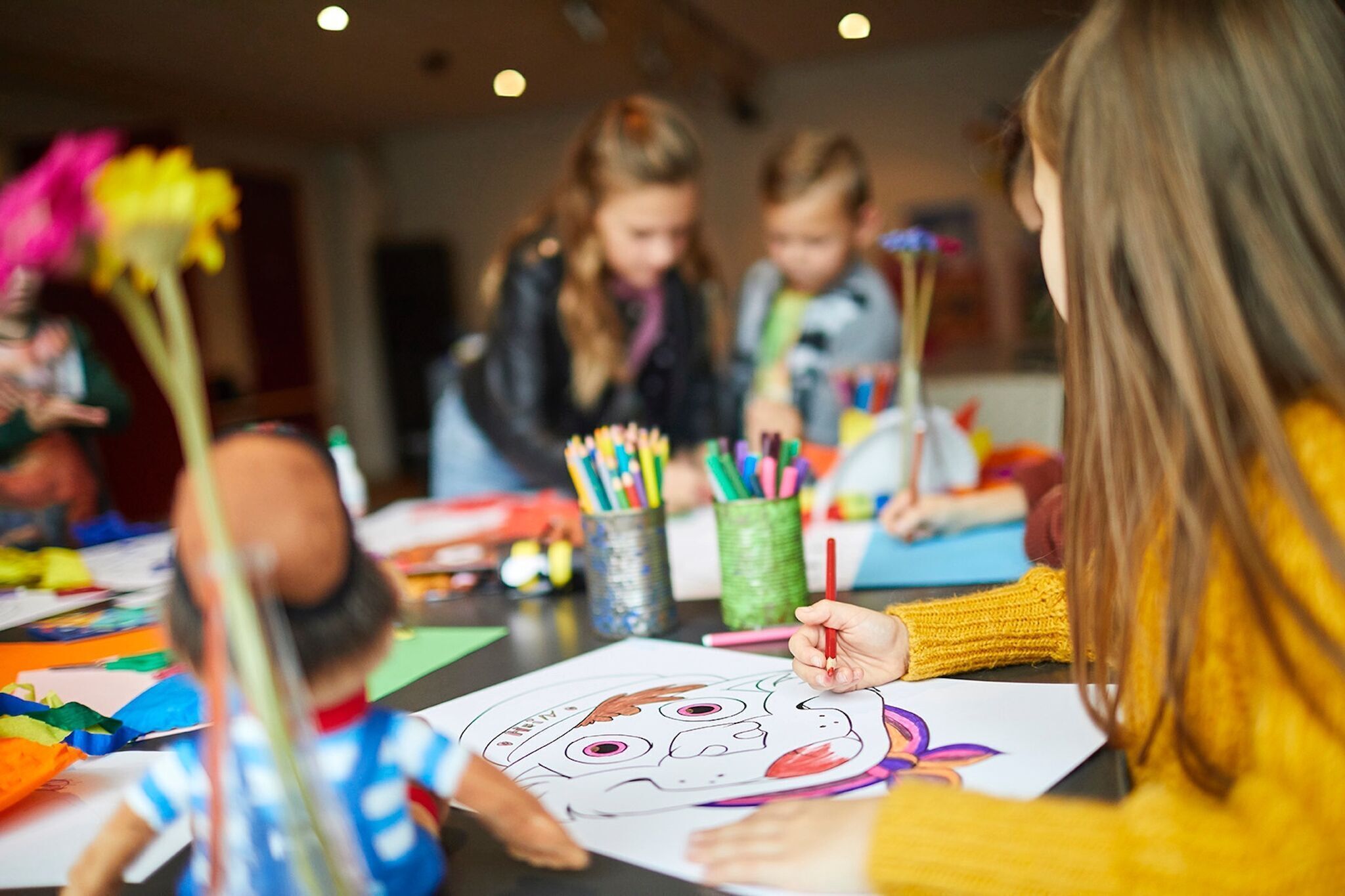 A group of children engaged in a coloring activity with various art supplies on a table.