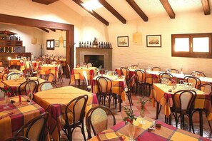 Ein Restaurant mit mehreren Tischen und Stühlen, einem Kamin und gerahmten Bildern an den Wänden.