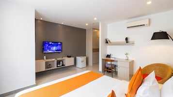 A modern hotel room with a large bed, a television, a desk, and a wicker chair.
