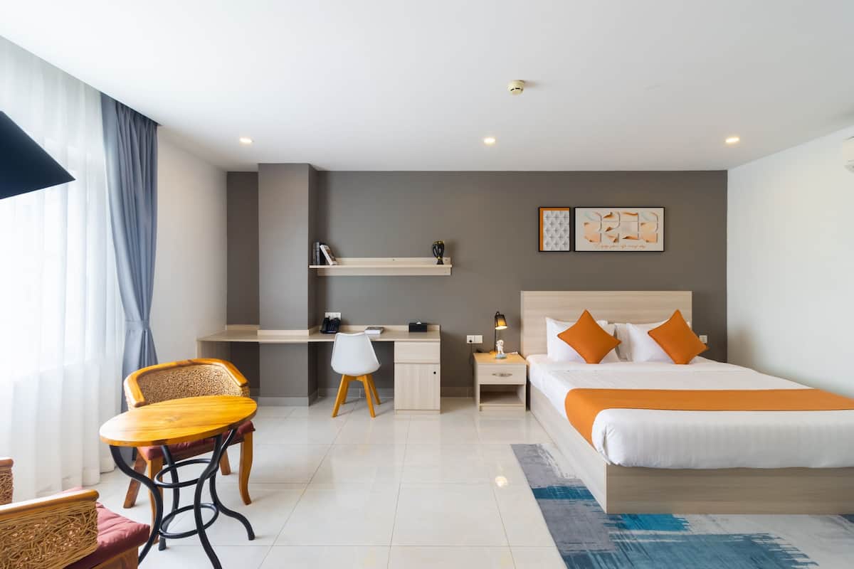 A hotel room with a bed, desk, chair, and a small table.