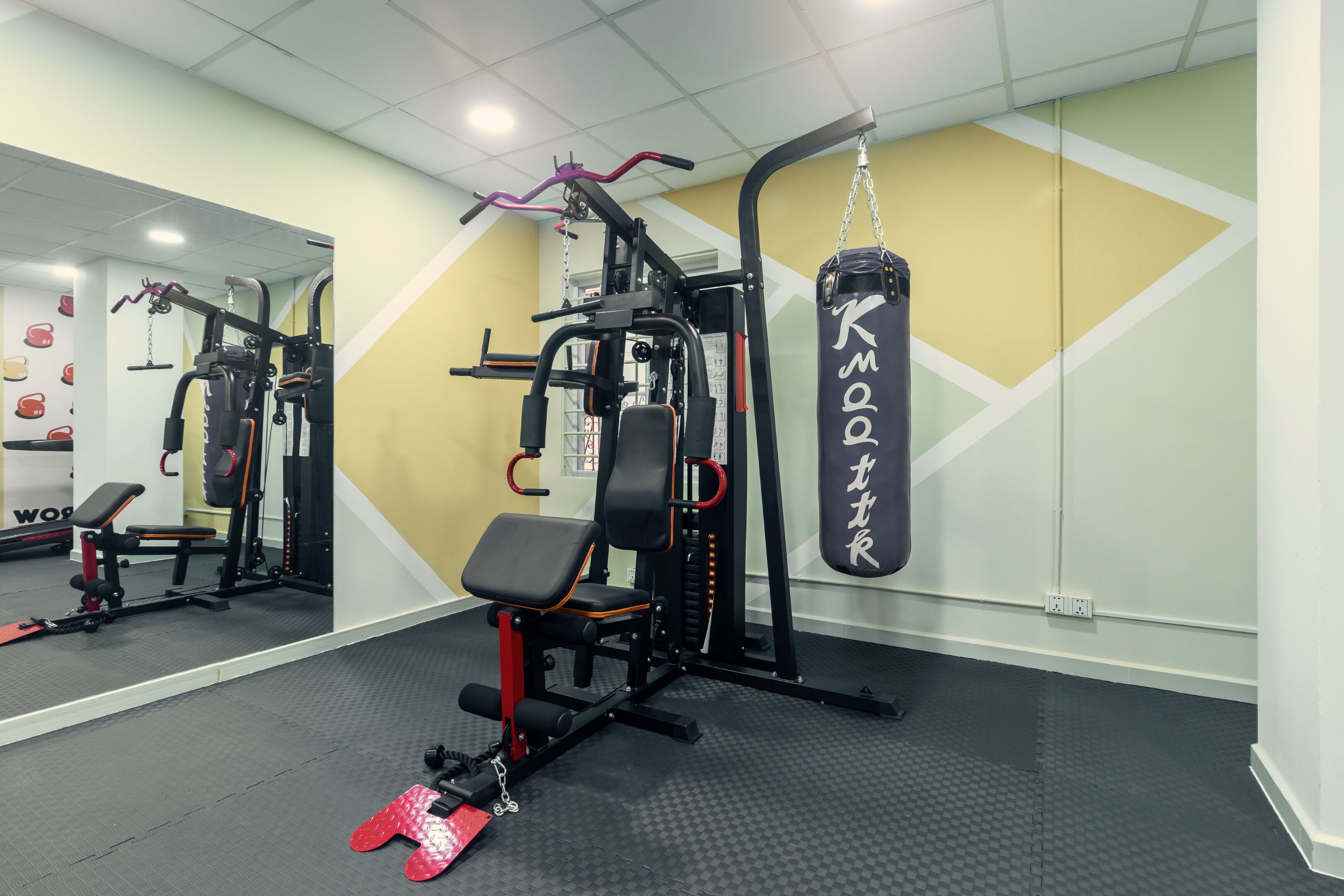 A gym with weightlifting equipment, a punching bag, and a mirror on the wall.
