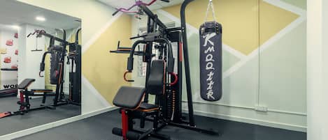 A gym with weightlifting equipment, a punching bag, and a mirror on the wall.