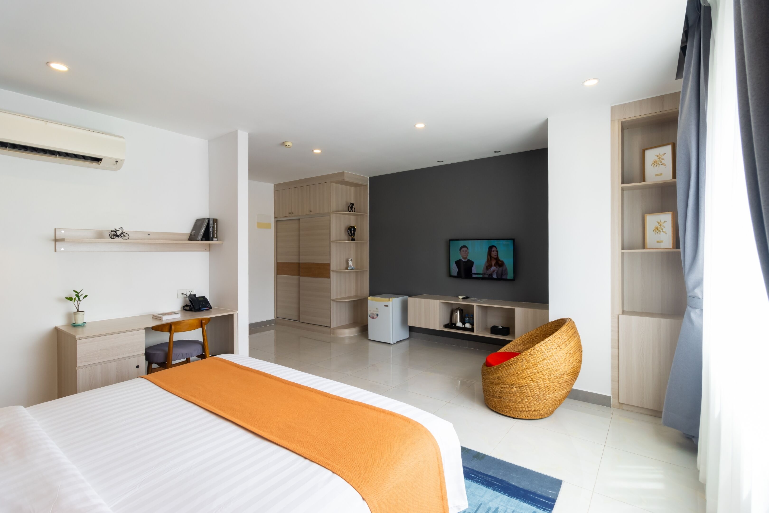 Ett modernt hotellrum med en säng, ett skrivbord, en TV och en sittgrupp.