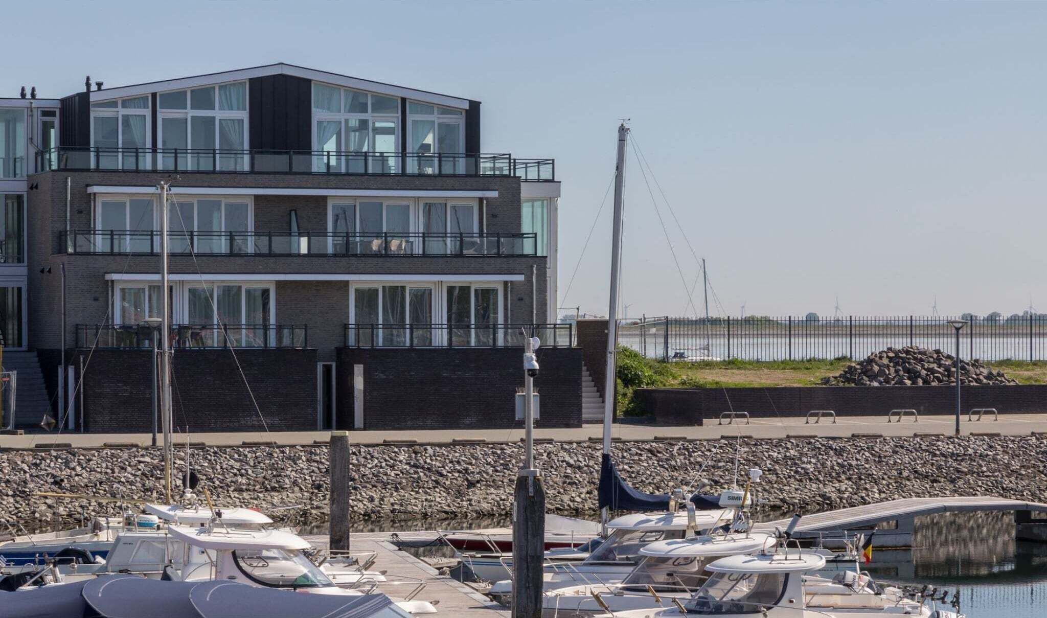 Een modern gebouw met meerdere balkons met uitzicht op een jachthaven.