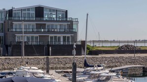 Ein modernes Gebäude mit mehreren Balkonen mit Blick auf eine Marina.