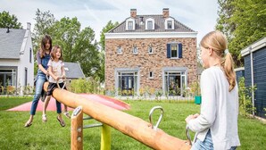 A playground with a seesaw and a brick house in the background. - Wellness Home in Maastricht w/ Sauna (Maastricht)